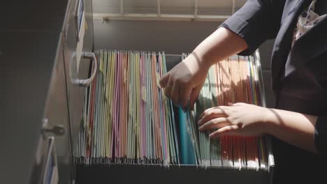 female staff searching for documents in the office filing cabinet