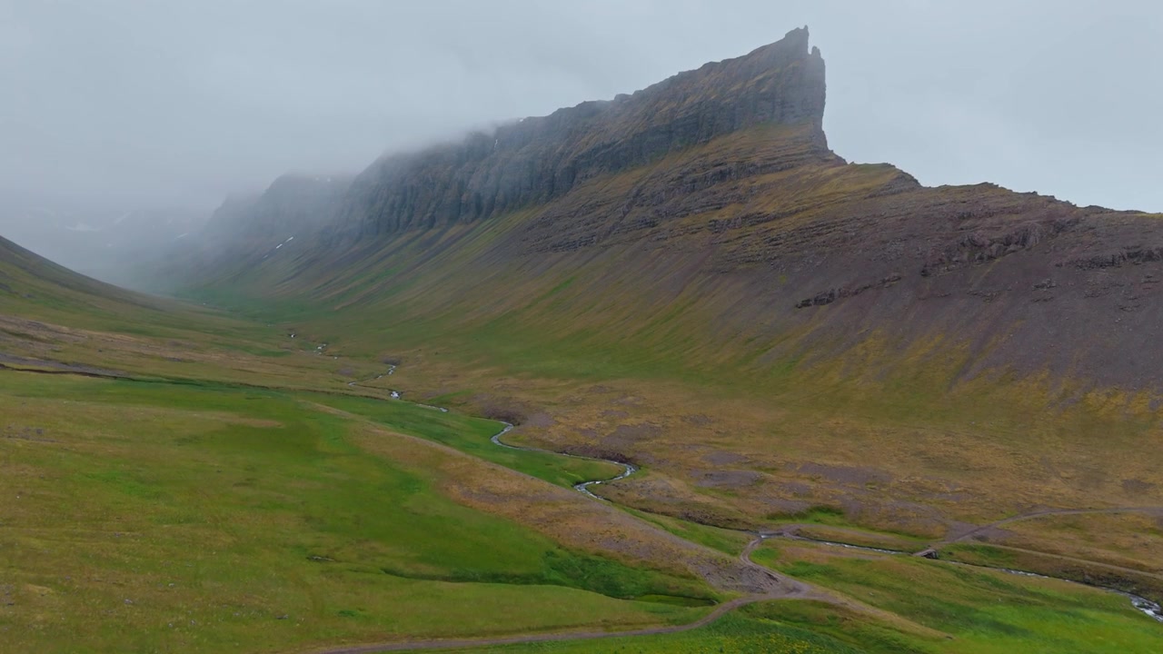 Impresionante toma aérea cinematográfica de la cordillera de Svalvogaviti en los Fiordos Occidentales de Islandia bajo un cielo sombrío y neblinoso. Captura la belleza auténtica y salvaje de la naturaleza nórdica.