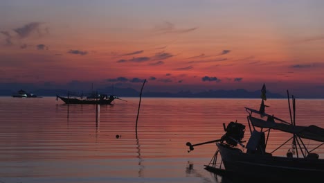 Beautiful-sunset-behind-fishing-boats-in-ocean-with-tiny-ripple-waves