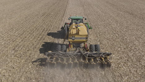 tractor with strip till machine performing strip tillage to prepare farm field for planting, aerial