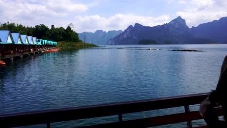 Female-Traveller-Taking-Photos-Of-Lake-Huts-From-Balcony-On-Cheow-Lan-Lake