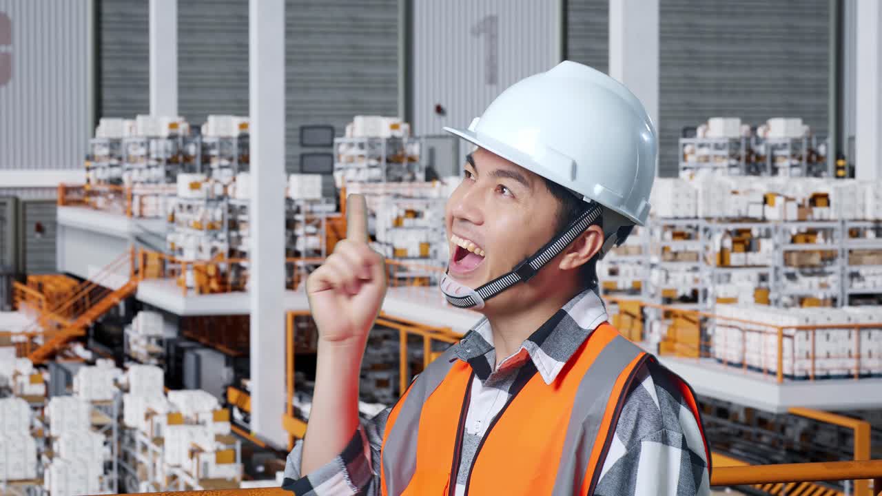안전 헬을 입은 아시아 남성 엔지니어가 배달 물품으로 가득 찬 선반과 함께 창고에 서서 무언가에 대해 생각하고 주위를 둘러보며 지표손가락을 들어 올립니다.