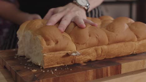 close up on cutting dinner rolls bun bread with long serrated knife