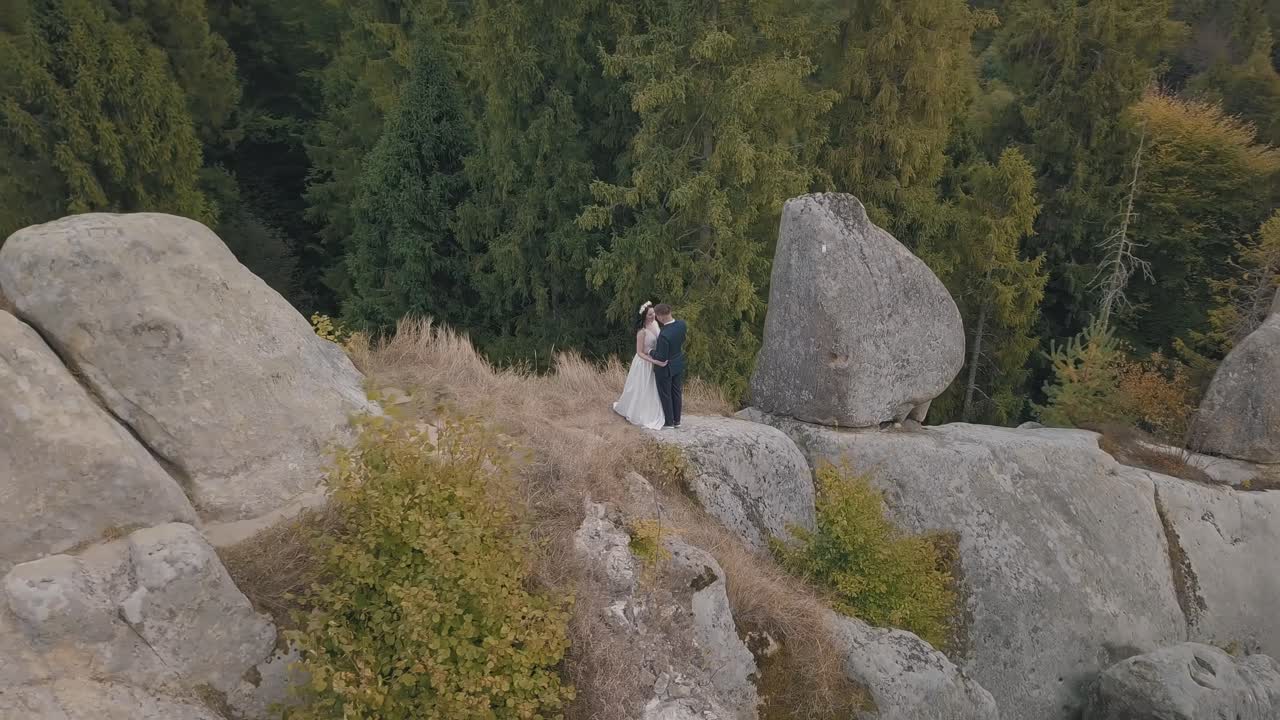 los recién casados están en una ladera alta de la montaña. el novio y la novia. vista aérea