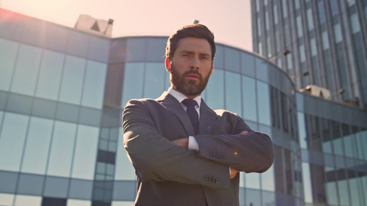 empresario confiado cruzando las manos posando a la luz del sol del centro de cerca.