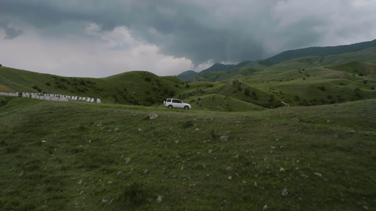 조지아의 아스핀자 근처에 흐린 시골길에 주차된 suv 자동차를 향해 날아가는 드론