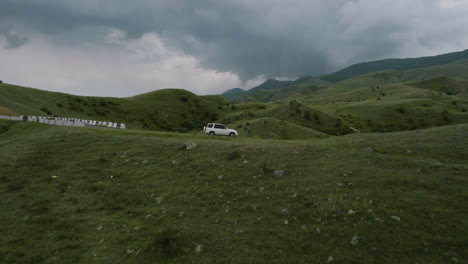 Drone-Volando-Hacia-Un-Automóvil-Suv-Estacionado-En-Un-Camino-Rural-Con-Cielo-Nublado-Cerca-De-Aspindza-En-Georgia