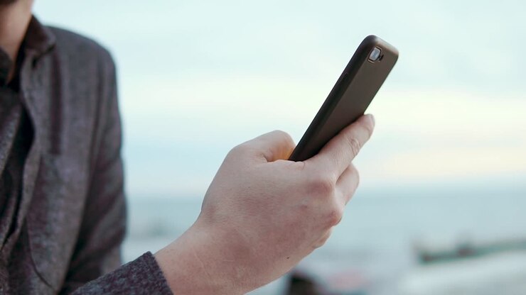 Uomo che usa uno smartphone in riva al mare