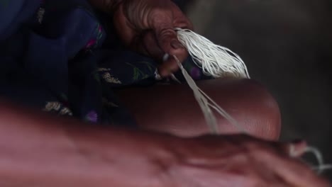 close up of black indian person manually assembling a traditional hammock with palm leaves