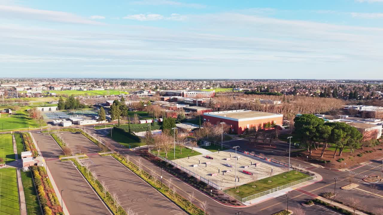 Bird's-eye drone view of a California community college campus in warm late afternoon light. Useful for education, academic, and urban planning projects. Rotating panning view