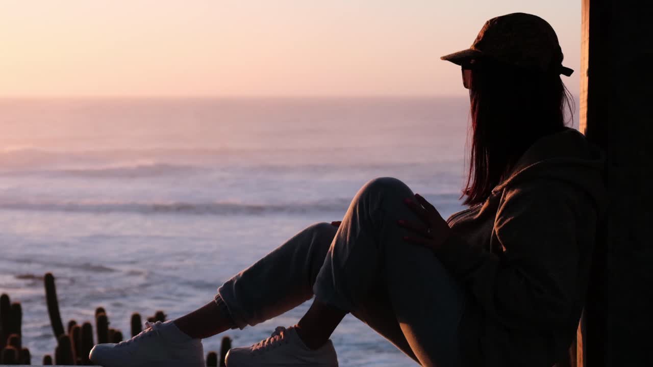 hermosa puesta de sol épica, con modelo femenino mirando al horizonte con su marcada silueta, mirando a pichilemu, punta de lobos, playa de surf, chile