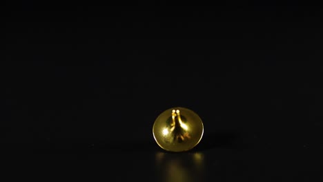 hand spins a golden top on black surface