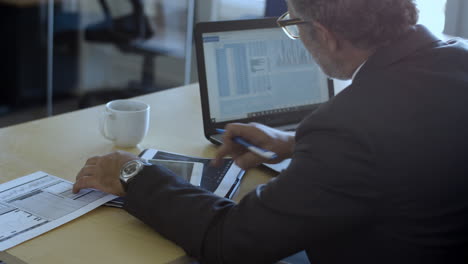 male finance professional using laptop and tablet