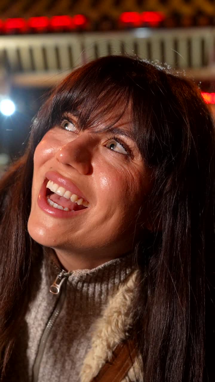 Giovane donna entusiasta che sorride e si guarda intorno di notte