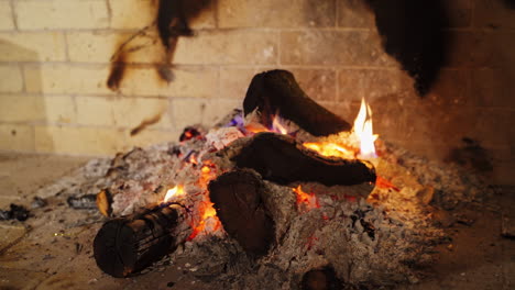 cozy fireplace. smoldering logs in ash. embers of burnt-out fire in fireplace at home. background of burning wood in slight flame. close-up.