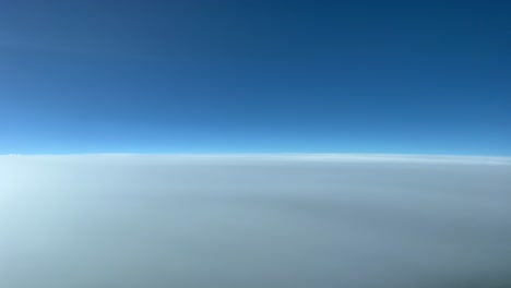 aerial view overfling a very high layer of stratus clouds at 12000 metres high from a jet cockpit