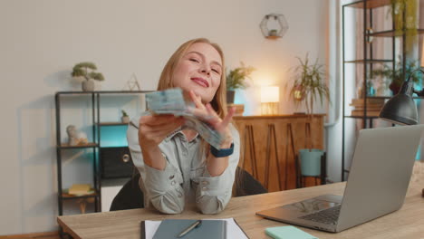 excited businesswoman freelancer holding fan of ukrainian hryvnias uah cash dancing at home office