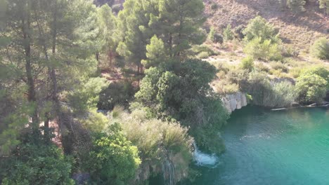 Kleine-Kaskaden-Zwischen-Der-Vegetation,-Die-Wasser-In-Einen-Türkisfarbenen-Teich-Gießen