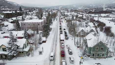 an aerial of a peaceful and beautiful snow-covered breckenridge, as cars drive through snow on the main road through the popular colorado mountain town for a ski vacation at the world famous resort.