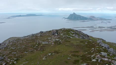 Excursionista-En-La-Cima-De-Una-Montaña-Rocosa-Con-Vista-A-Las-Pintorescas-Islas-Y-Fiordos-En-Noruega---órbita-Aérea