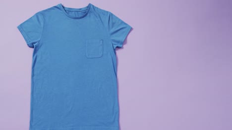 Video-Eines-Blauen-T-Shirts-Mit-Etikett-Und-Kopierraum-Auf-Violettem-Hintergrund