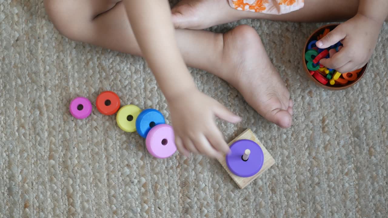 niño jugando con juguetes de bebé en la cama, concepto de desarrollo infantil.