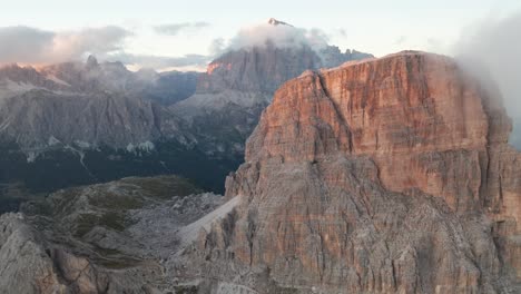 aerial forward flight over lighting nuvolau group mountains in dolomites during golden sunset