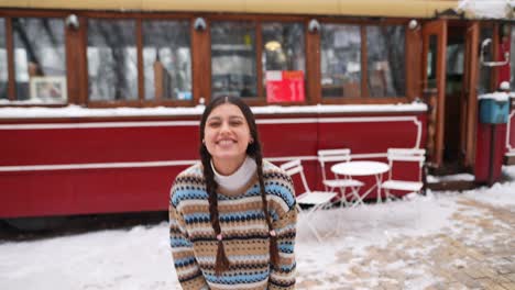 woman blowing a kiss in the snow outside a vintage cafe
