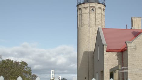 Old-Mackinac-Point-Lighthouse-in-Mackinaw-City,-Michigan-with-cinematic-video-shot-on-dolly-to-reveal-Mackinac-Bridge-and-white-picket-fence