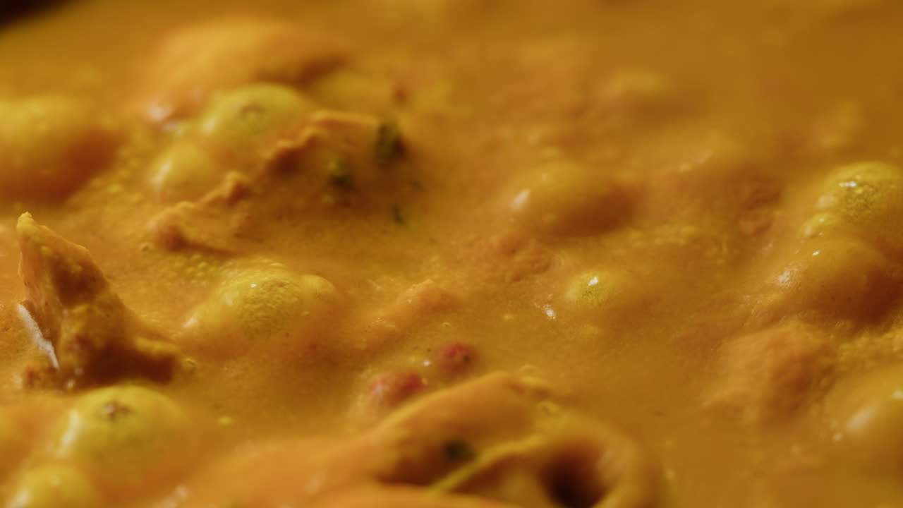 Yellow boiling sauce on pan close-up. Asian cuisine concept. Curry is a dish with a sauce seasoned with spices. Curries may contain fish, meat, poultry, or shellfish, either alone or in combination with vegetables. Others are vegetarian.