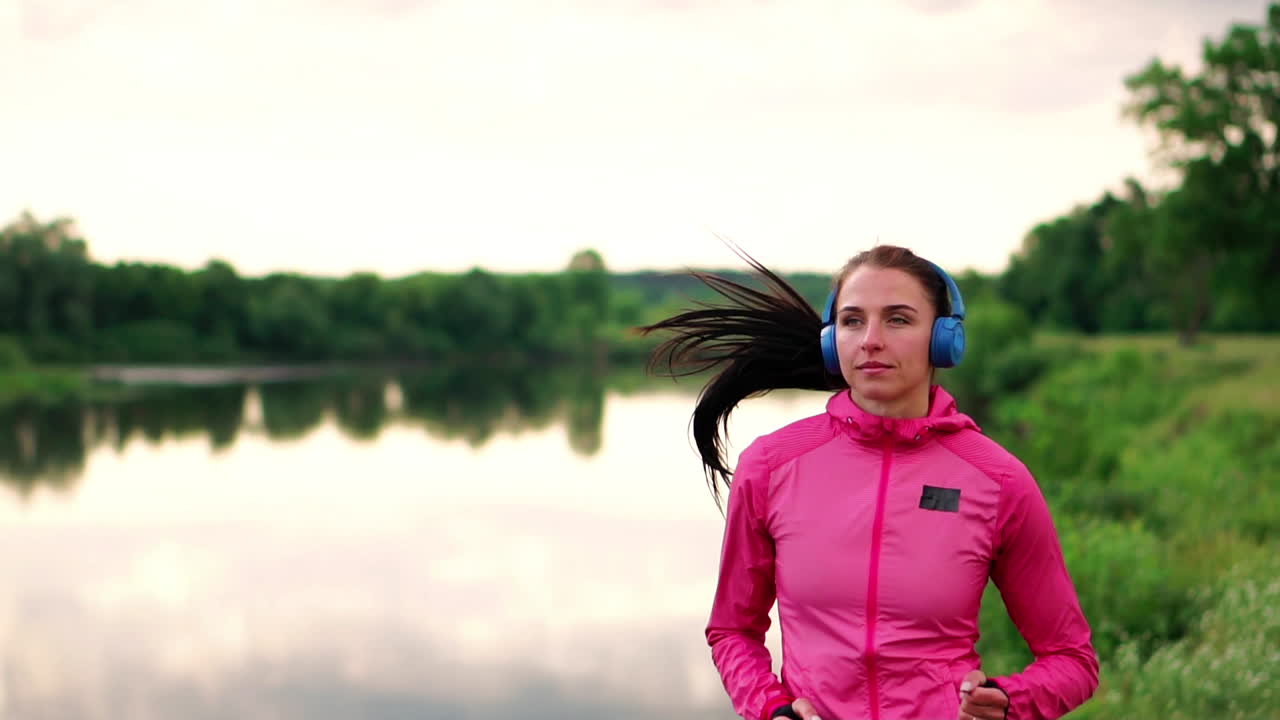 una carrera matutina en el parque cerca del estanque en los rayos soleados del amanecer, la niña se está preparando para mariano y llevar un estilo de vida saludable