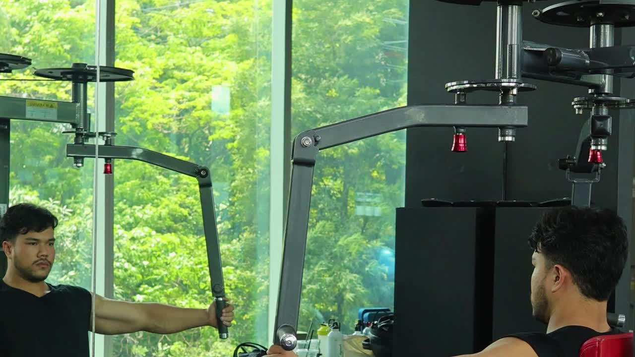 Young man in athletic wear performs controlled chest fly repetitions on a machine in gym