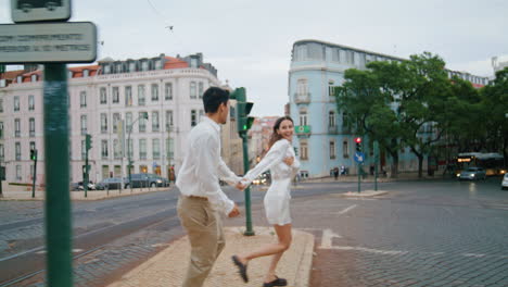 excited pair running urban street. laughing man woman having fun crossing road