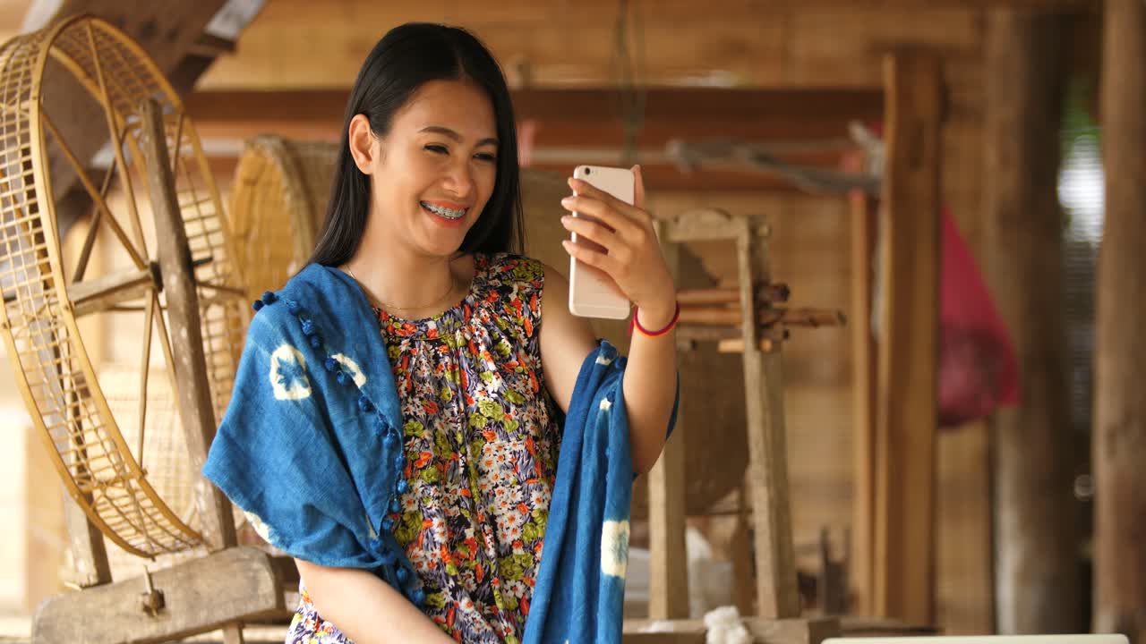Woman taking a selfie in a traditional weaving setting