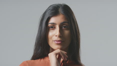 Studio-Portrait-Of-Serious-Young-Businesswoman-Resting-Face-On-Hand-Against-Plain-Background