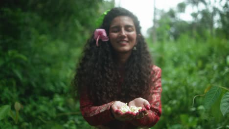 a joyful woman with dark curly hair laughs brightly, holding delicate flowers out