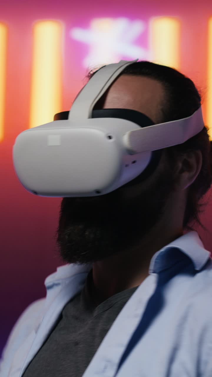 Video verticale Uomo moderno in una scena notturna illuminata al neon che usa occhiali VR high-tech