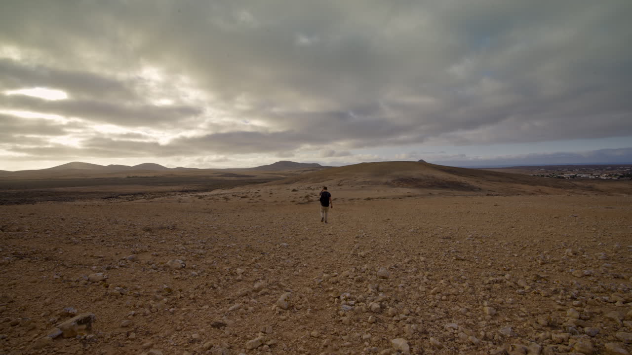 lonely person walking away in empty desolate rocky raw landscape
