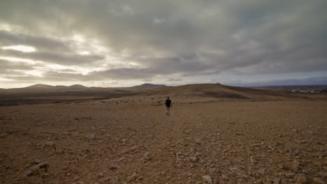 persona solitaria caminando en el vacío desolado paisaje rocoso crudo