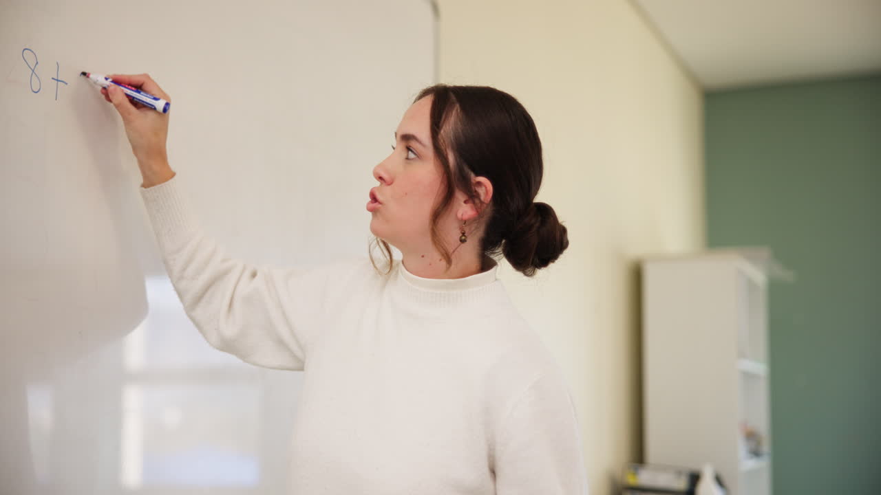 Woman writing math on whiteboard