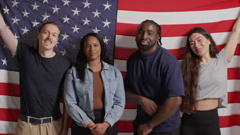 Studio-Portrait-Shot-Of-Multi-Cultural-Group-Of-Friends-Holding-American-Flag-Behind-Them-Celebrating-4th-July-Independence-Day-6