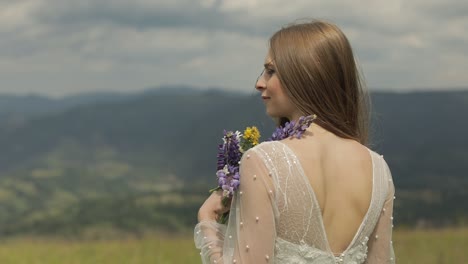 beautiful bride in a white dress posing with flowers in a field