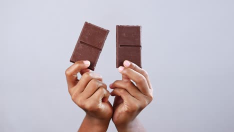 hands holding two pieces of dark chocolate