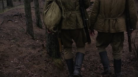 dos soldados de la segunda guerra mundial caminando en un bosque con rifles y cascos y botas fumando cigarrillos