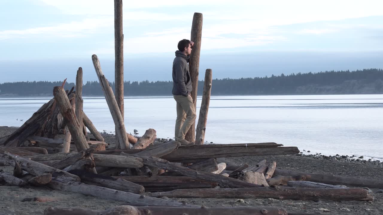 hombre admirando la impresionante vista del paisaje, se paró sobre madera a la deriva en la costa de la isla de vancouver, canadá