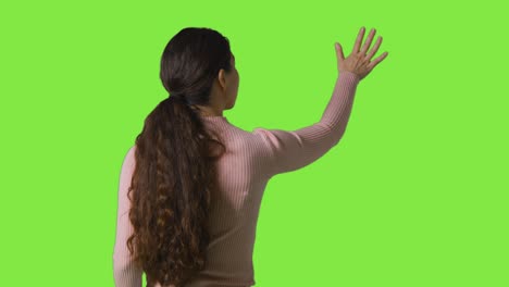Rückansicht-Studioaufnahme-Einer-Frau,-Die-In-Einer-VR-Umgebung-Vor-Einem-Grünen-Bildschirm-Schaut-Und-Sie-Berührt