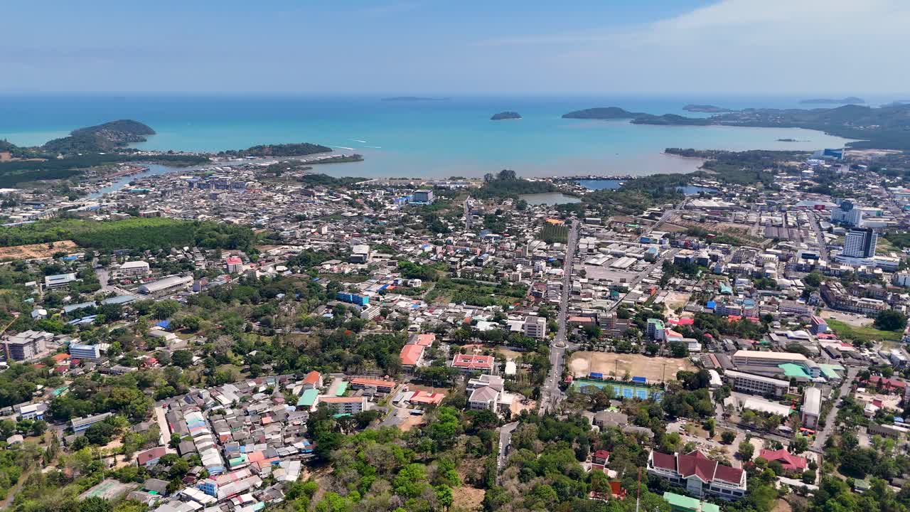Drone footage captures Phuket's vibrant cityscape and stunning Andaman Sea, showcasing lush greenery and urban development under clear skies
