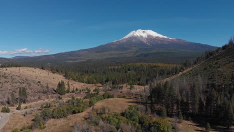 Aufsteigende-Luftaufnahme-Des-Schneebedeckten-Mount-Shasta-Und-Der-Davor-Liegenden-Autobahn