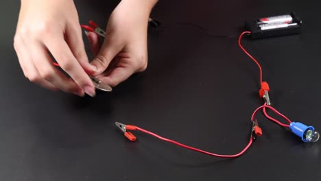 hands connect wires to test electric circuit