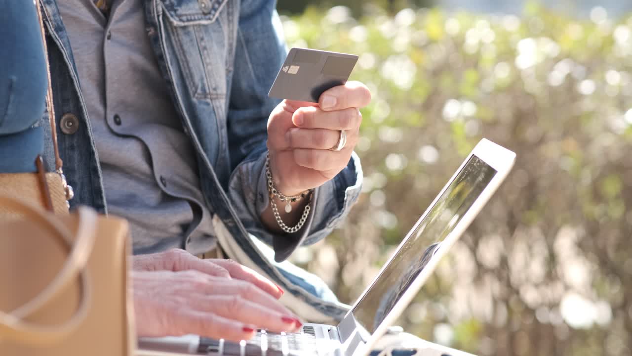 Crop woman typing on laptop while man holding credit card